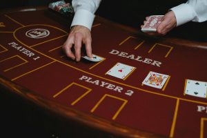 Cận cảnh bàn blackjack với dealer đang chia bài trên nền nỉ xanh